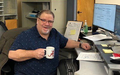 Scott at his desk holding a cup of coffee