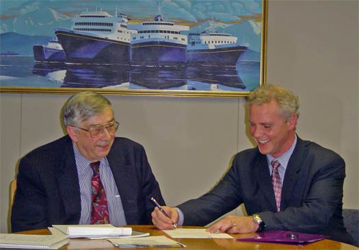 Mike Barton and Grey Mitchell seated in front of painting of ferry boats