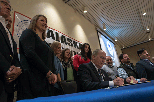 A group of people smile for cameras at the bill signing ceremony